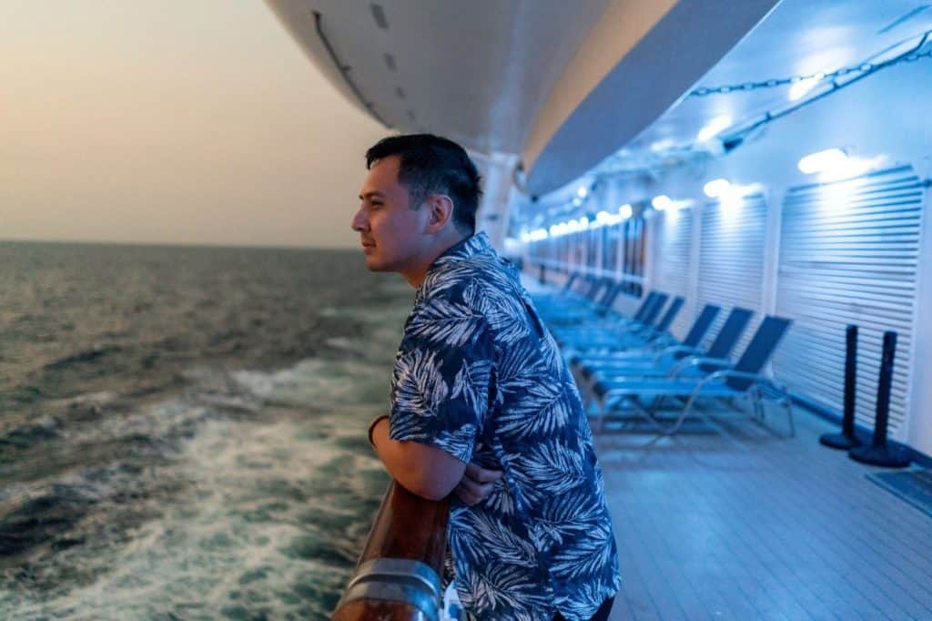 East Indian Passenger looks out from ocean liner over railing